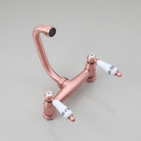 Koperkleurige landelijke muurkraan met keramische handgrepen