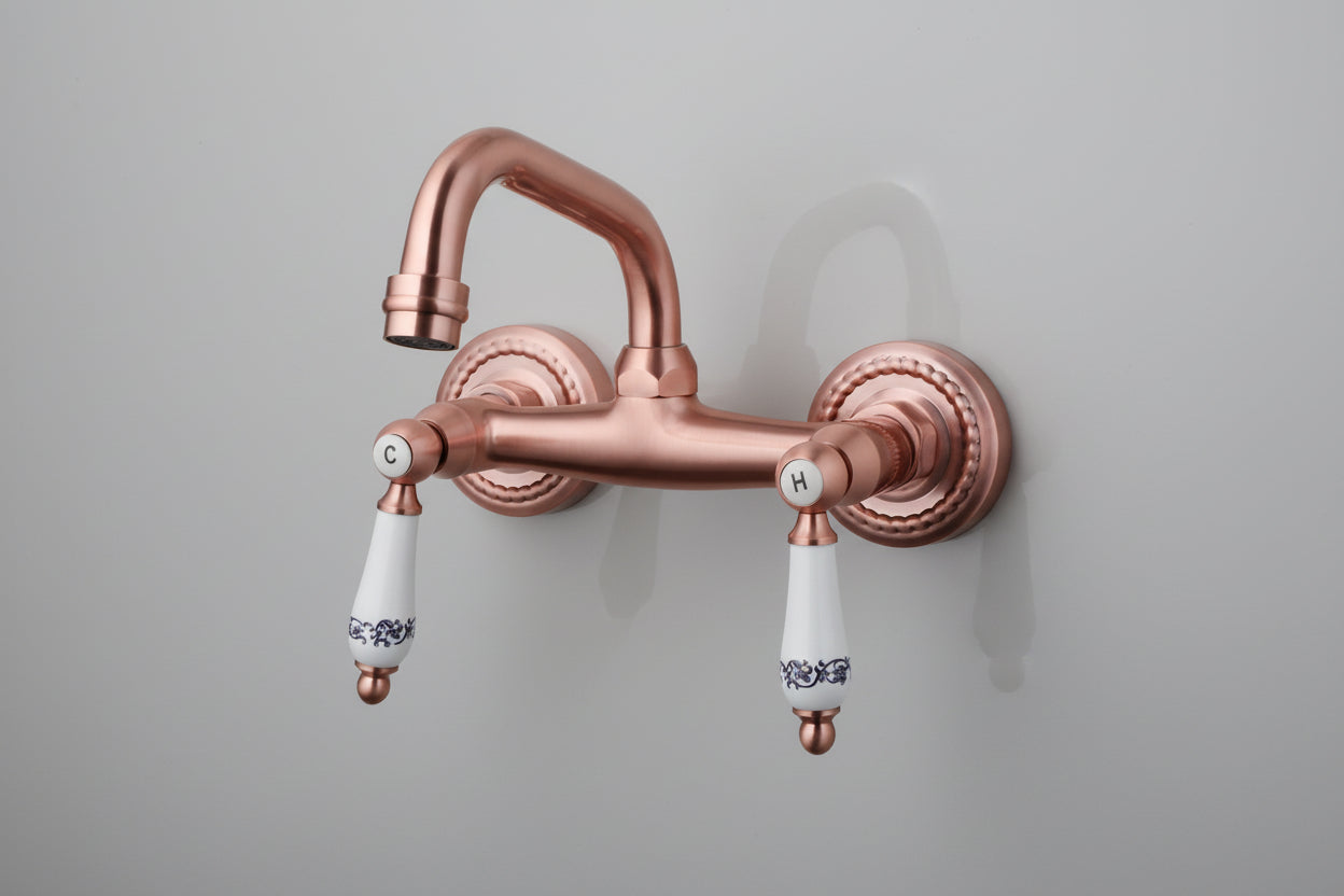 Koperkleurige landelijke muurkraan met keramische handgrepen